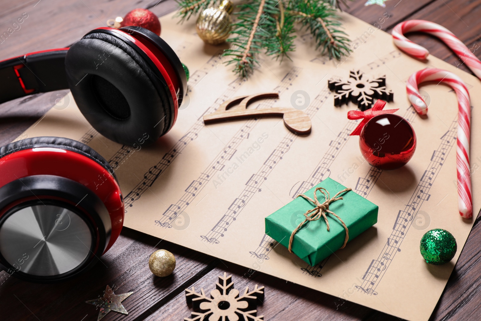 Photo of Christmas decorations, headphones and music sheets on wooden table