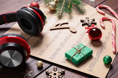 Christmas decorations, headphones and music sheets on wooden table