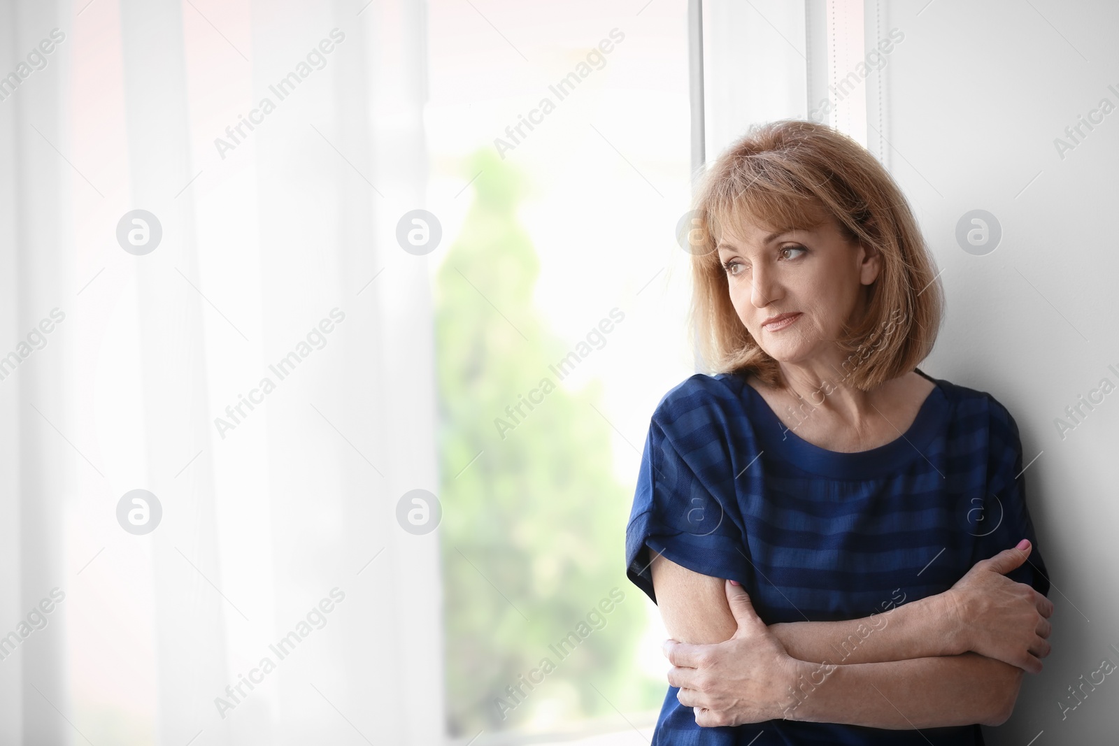 Photo of Senior woman suffering from depression near window