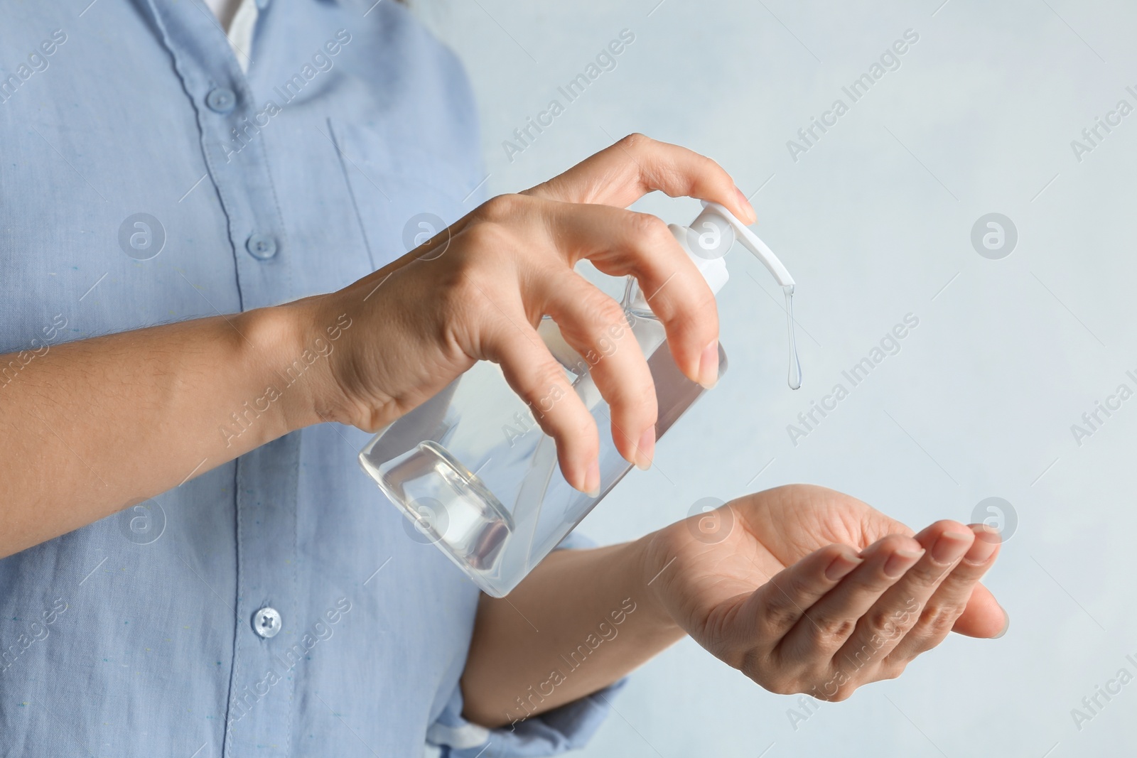 Photo of Woman applying antiseptic gel onto hand against light background, closeup. Virus prevention
