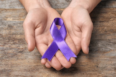 Photo of Man with purple awareness ribbon on wooden background, closeup