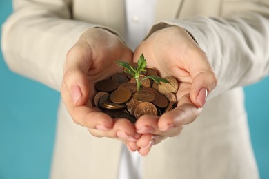 Photo of Woman holding coins with green sprout on turquoise background, closeup. Investment concept