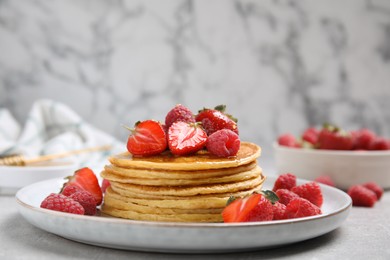 Photo of Tasty pancakes with ripe fresh berries and honey on light grey table, space for text