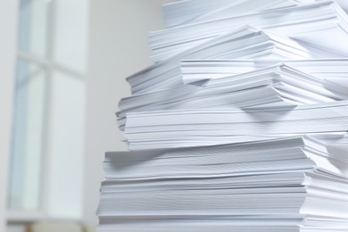 Photo of Stack of paper sheets against blurred background, closeup. Space for text