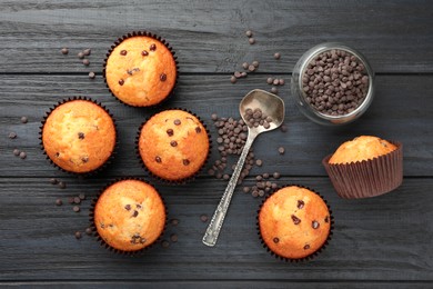 Photo of Delicious freshly baked muffins with chocolate chips on dark gray table, flat lay