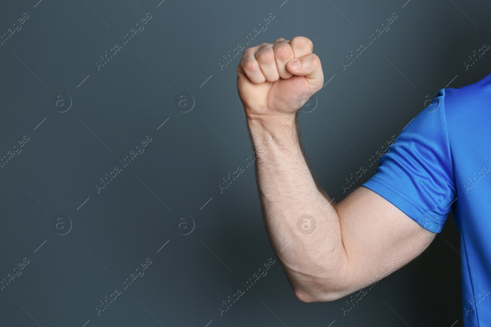 Photo of Young man showing clenched fist on color background. Space for text