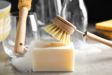 Cleaning brush and soap bar for dish washing on grey table, closeup