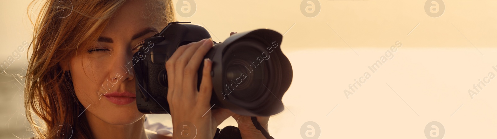 Image of Photographer taking photo with professional camera outdoors, space for text. Banner design