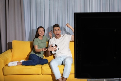 Couple watching soccer match on TV in living room