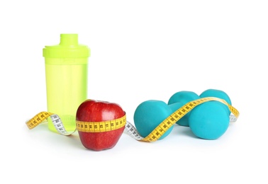 Photo of Apple, measuring tape and dumbbells on white background. Concept of weight loss