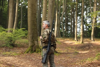 Photo of Man with hunting rifle wearing camouflage in forest