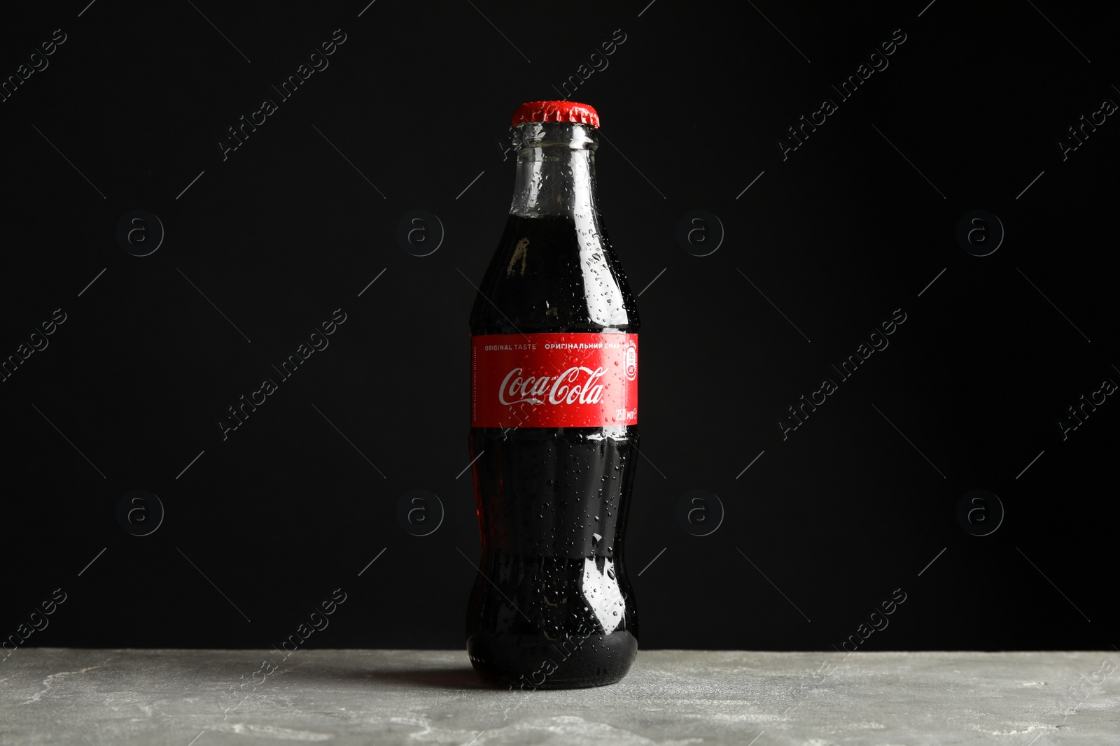 Photo of MYKOLAIV, UKRAINE - NOVEMBER 15, 2018: Bottle of Coca Cola on table against black background