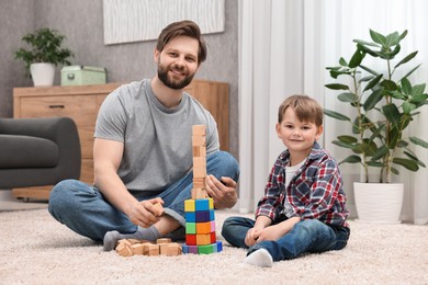 Photo of Happy dad and son near tower of cubes at home