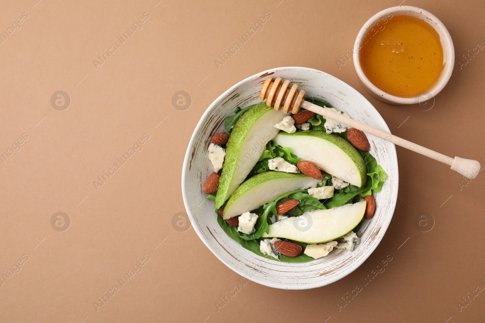 Photo of Delicious pear salad in bowl, honey and dipper on beige background, top view. Space for text