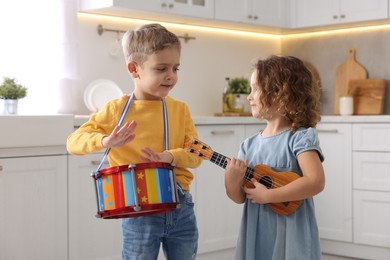 Photo of Little children playing toy musical instruments in kitchen