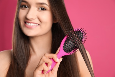 Woman with hair brush on color background, closeup. Space for text