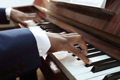 Photo of African-American man playing piano, closeup. Talented musician