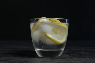 Glass of vodka with lemon slices and ice on grey table