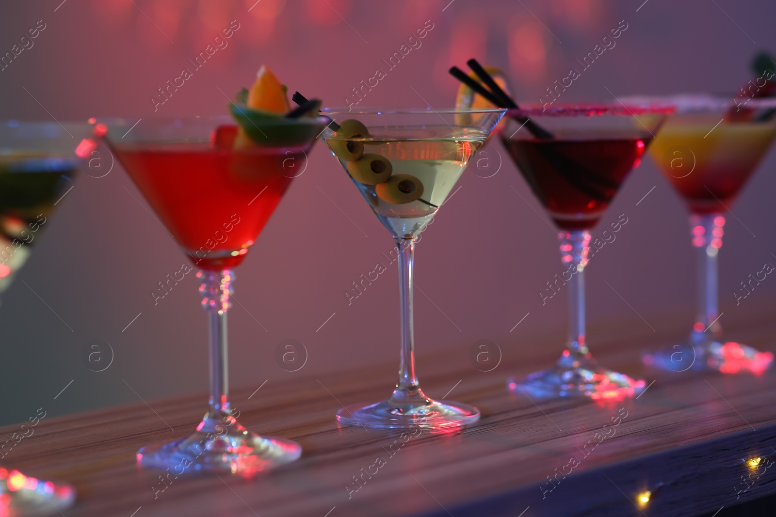 Photo of Different martini cocktails on table in bar, closeup