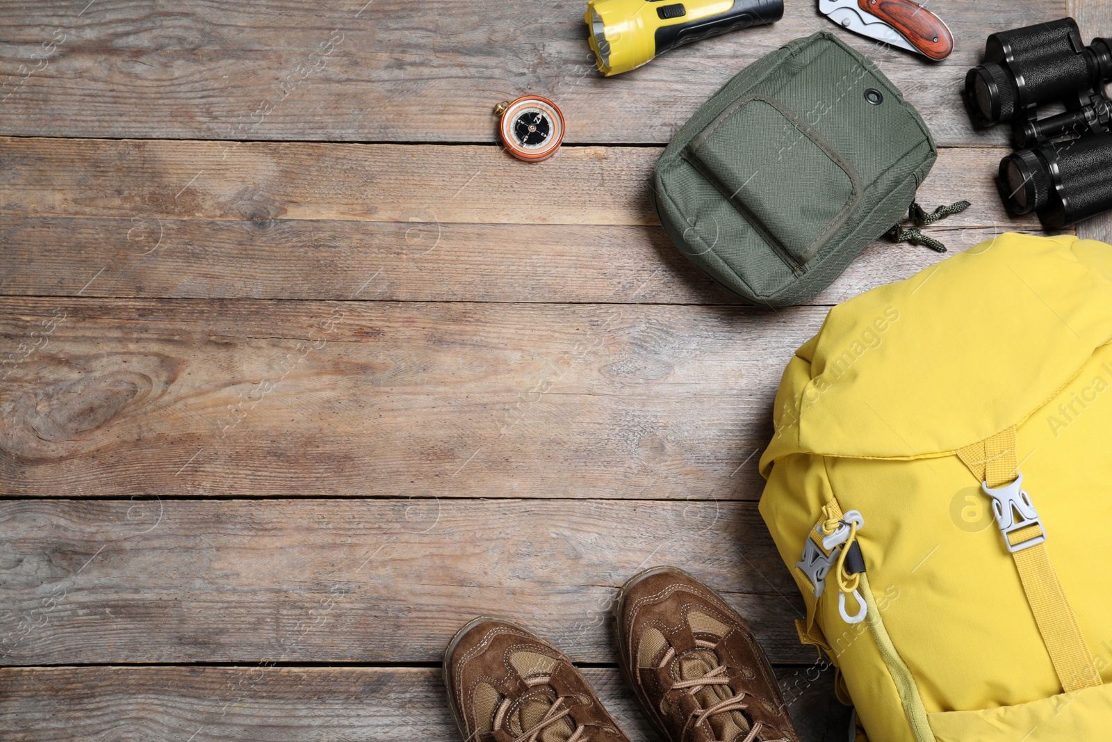 Photo of Flat lay composition with tourist backpack and other camping equipment on wooden background, space for text