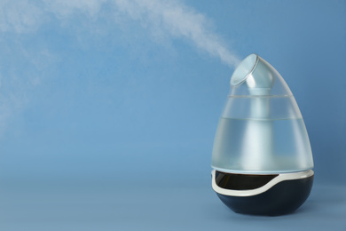Modern air humidifier on light blue background. Space for text