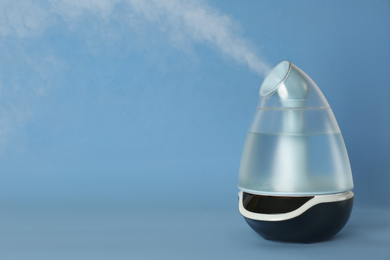 Photo of Modern air humidifier on light blue background. Space for text