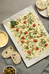 Photo of Fresh butter board with cut olives, pepper and bread on grey table, flat lay