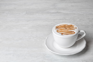 Photo of Cup of caramel macchiato on light table, space for text