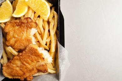 Photo of Container with British traditional fish and potato chips on light background, top view. Space for text