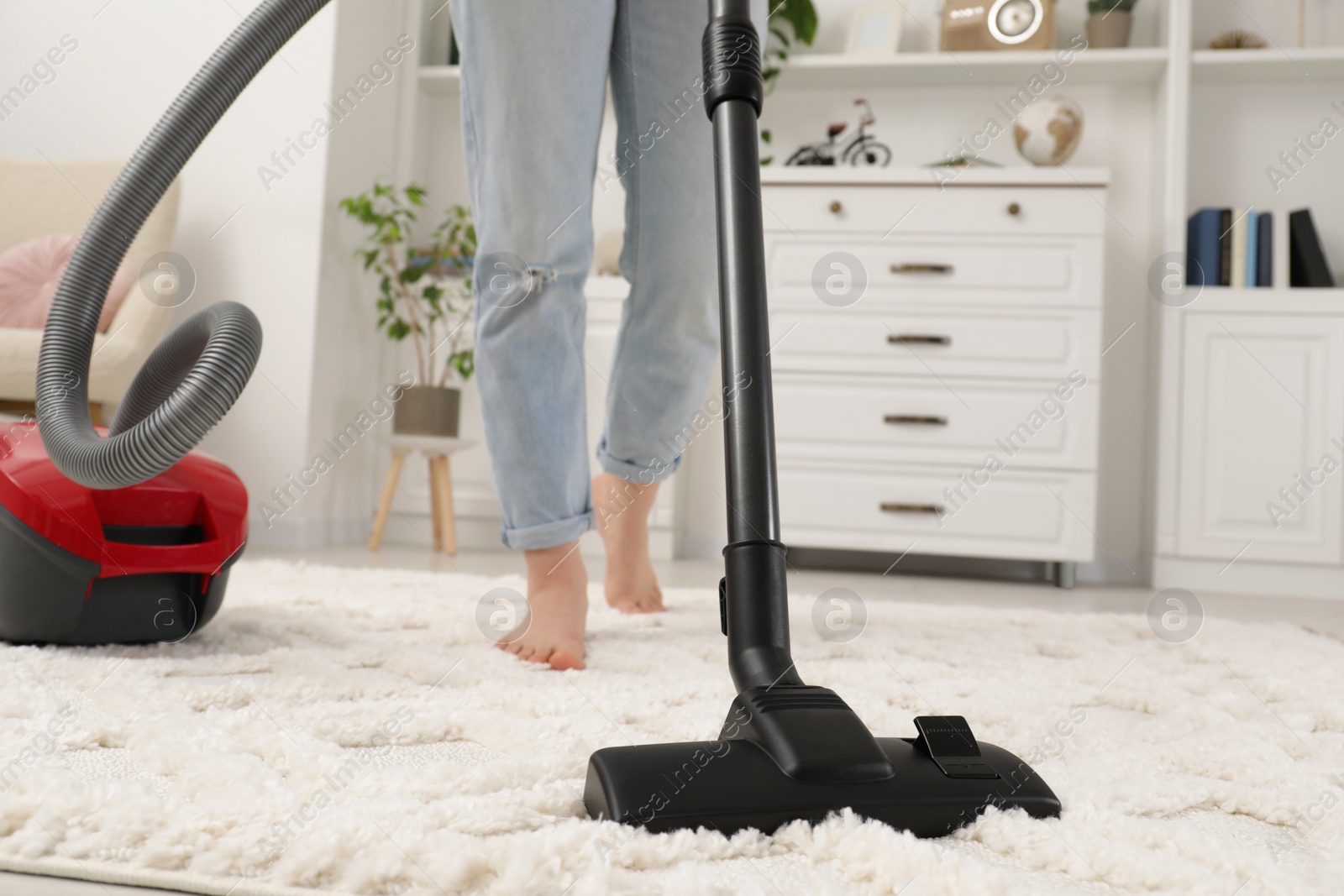 Photo of Woman cleaning carpet with vacuum cleaner at home, closeup