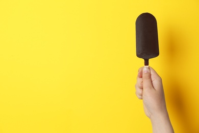 Photo of Woman holding delicious ice cream with chocolate against color background, space for text