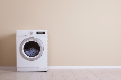 Washing machine near color wall, space for text. Laundry day