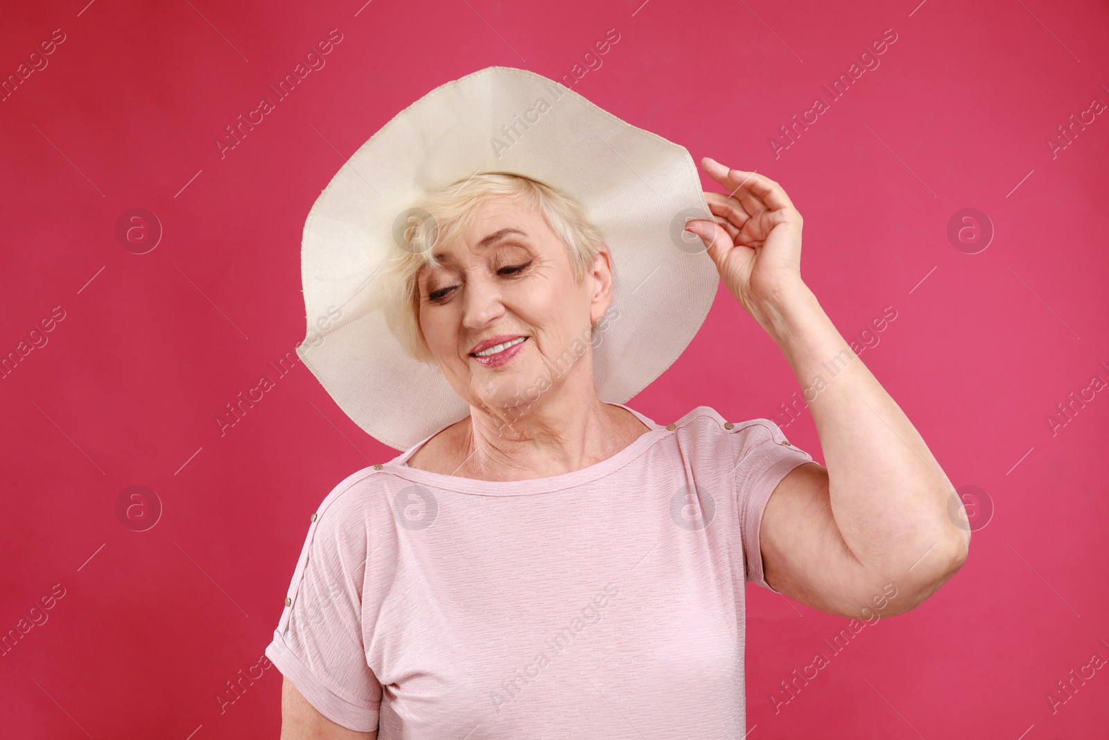 Photo of Senior woman with hat on crimson background