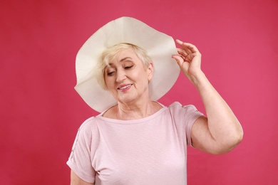 Senior woman with hat on crimson background