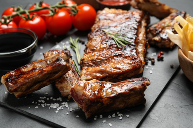 Photo of Delicious grilled ribs on black table, closeup