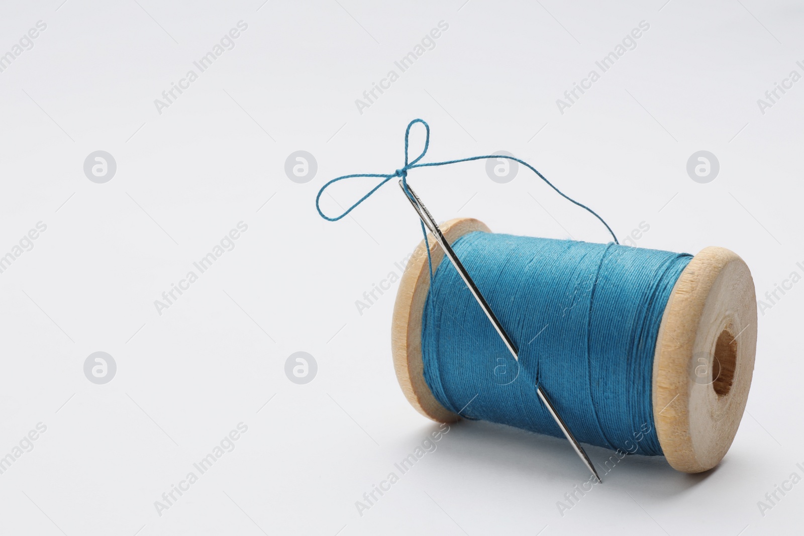 Photo of Light blue sewing thread with needle on white background