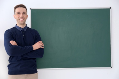 Photo of Young male teacher standing near blackboard on white background