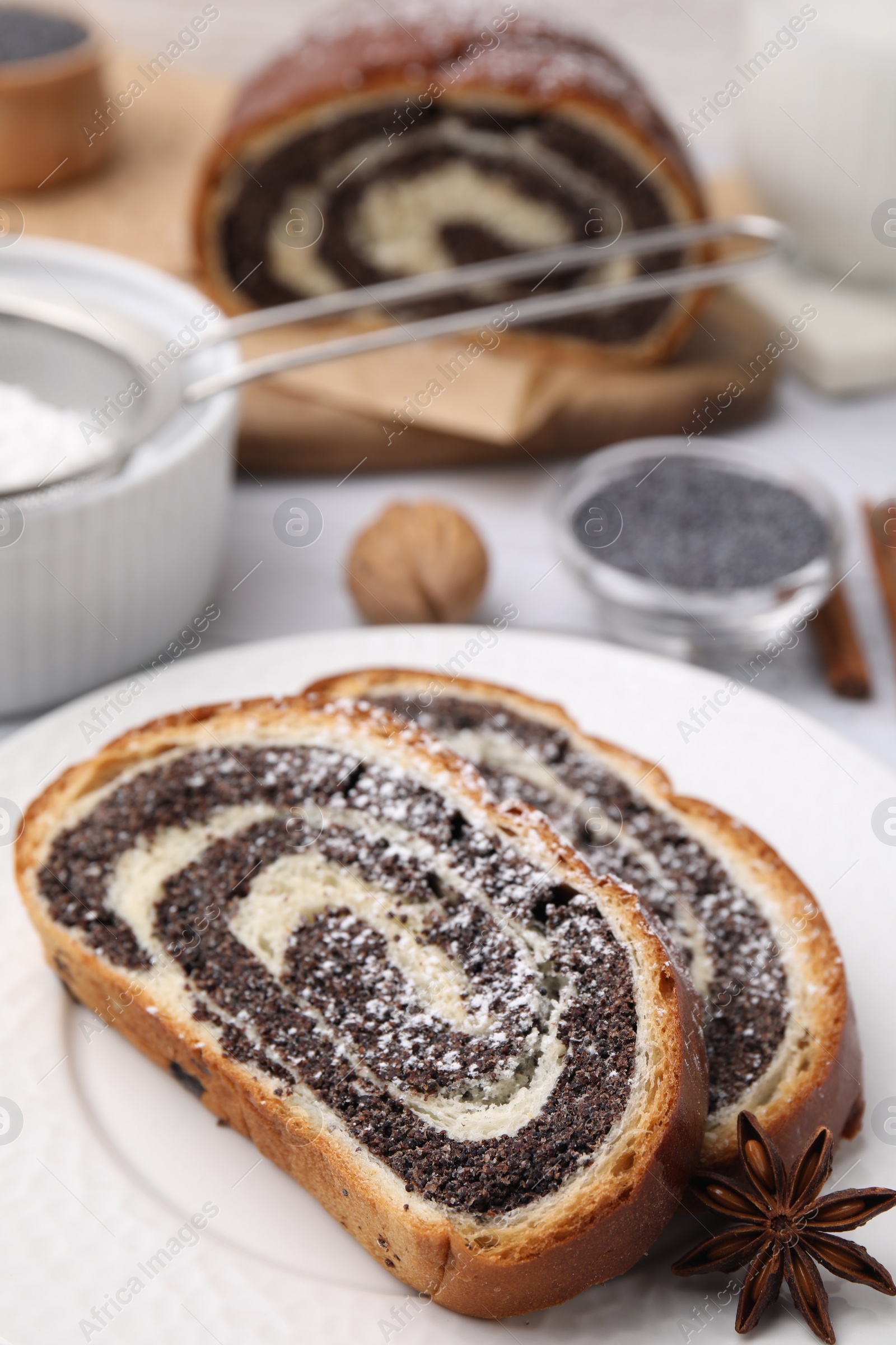 Photo of Slices of poppy seed roll and anise star on table, closeup with space for text. Tasty cake