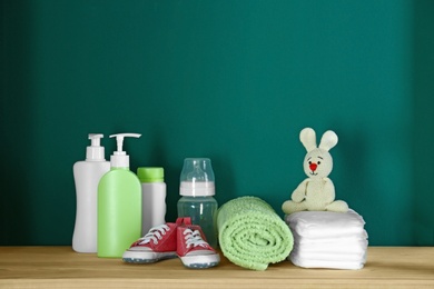 Bathroom accessories and toy for baby room interior on wooden table near turquoise wall