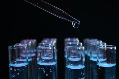 Photo of Dripping reagent into test tube on black background, closeup. Laboratory analysis