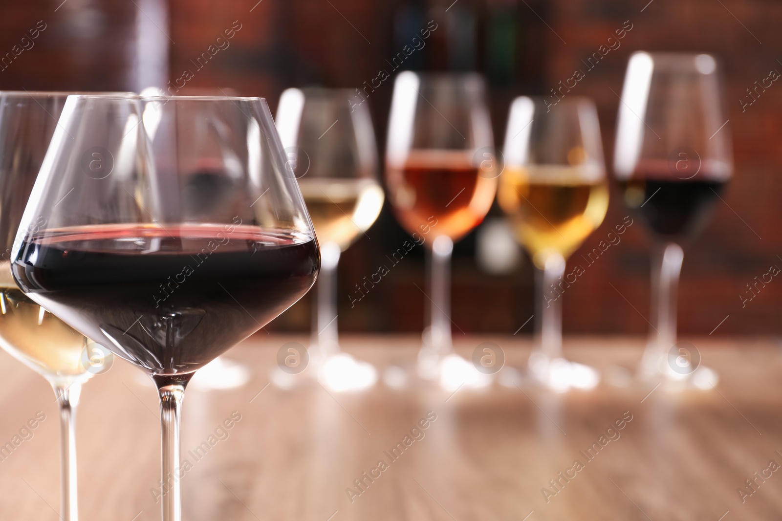 Photo of Tasty red and white wines in glasses against blurred background, space for text