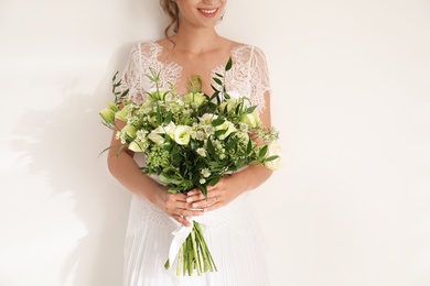 Photo of Young bride wearing wedding dress with beautiful bouquet on light background, closeup