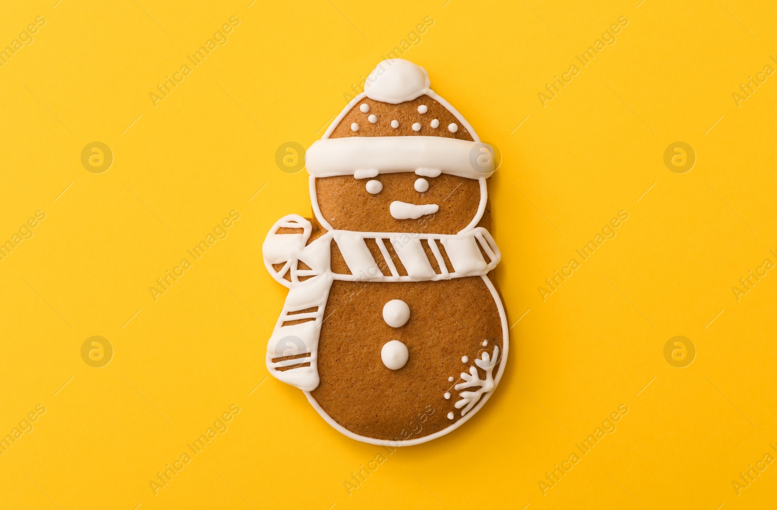 Photo of Christmas snowman shaped gingerbread cookie on yellow background, top view