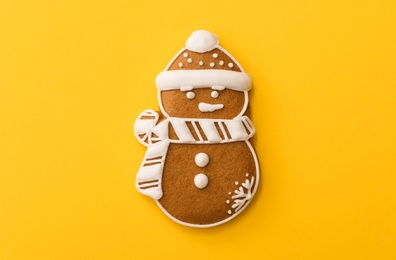 Christmas snowman shaped gingerbread cookie on yellow background, top view