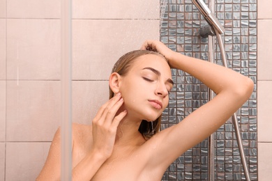 Beautiful young woman taking shower at home