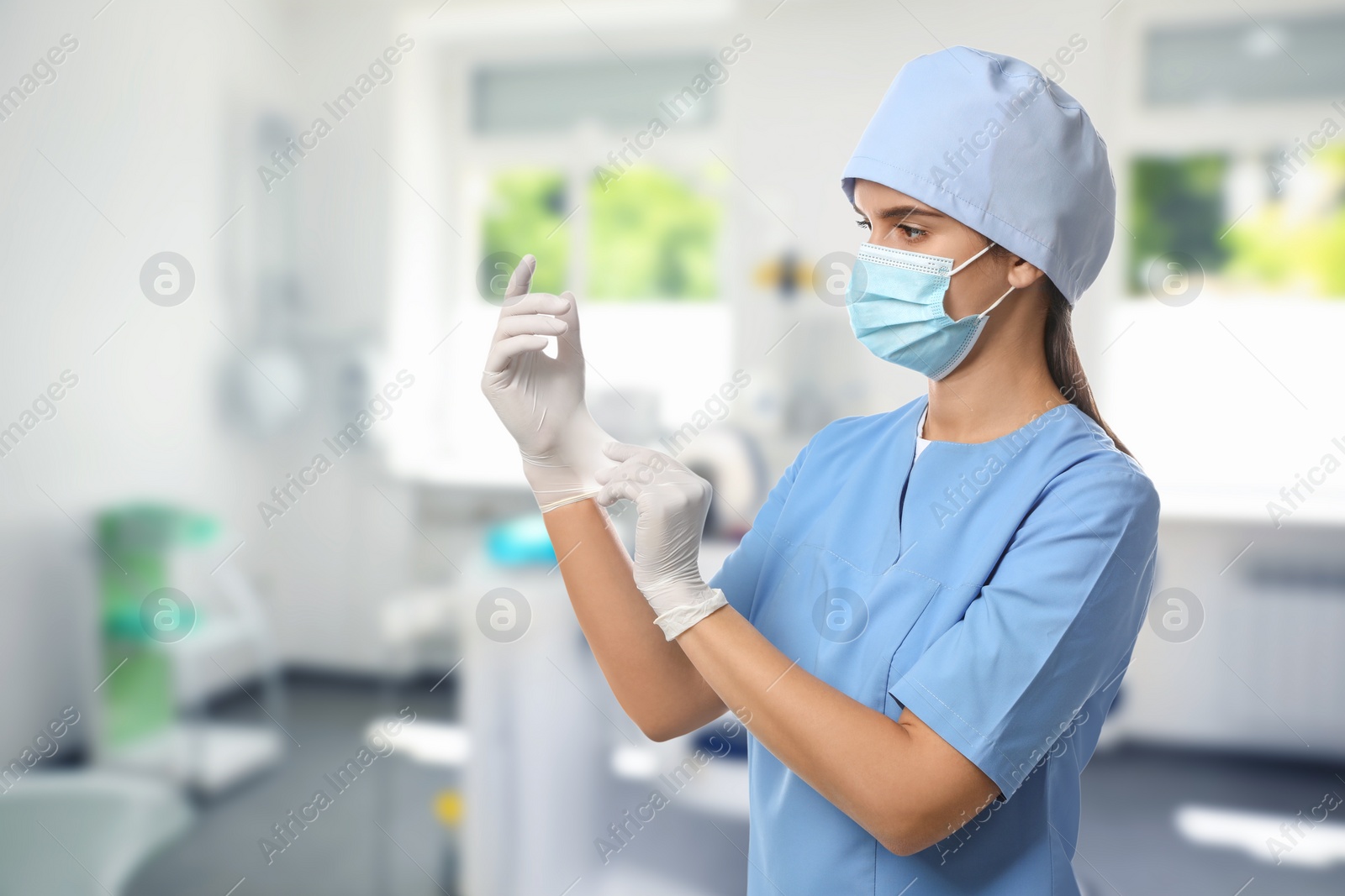 Image of Nurse in uniform putting on gloves at hospital
