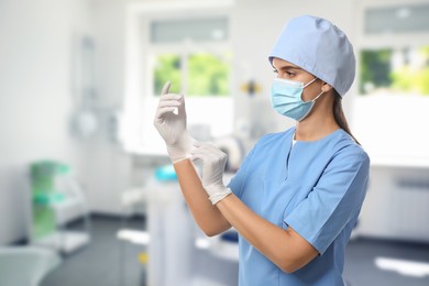 Image of Nurse in uniform putting on gloves at hospital