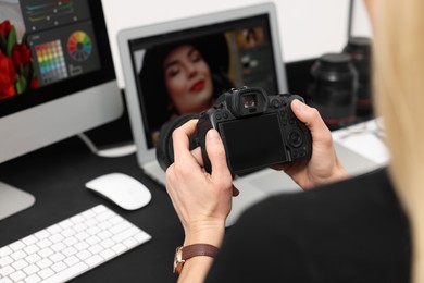 Photo of Professional photographer with digital camera at table indoors, closeup