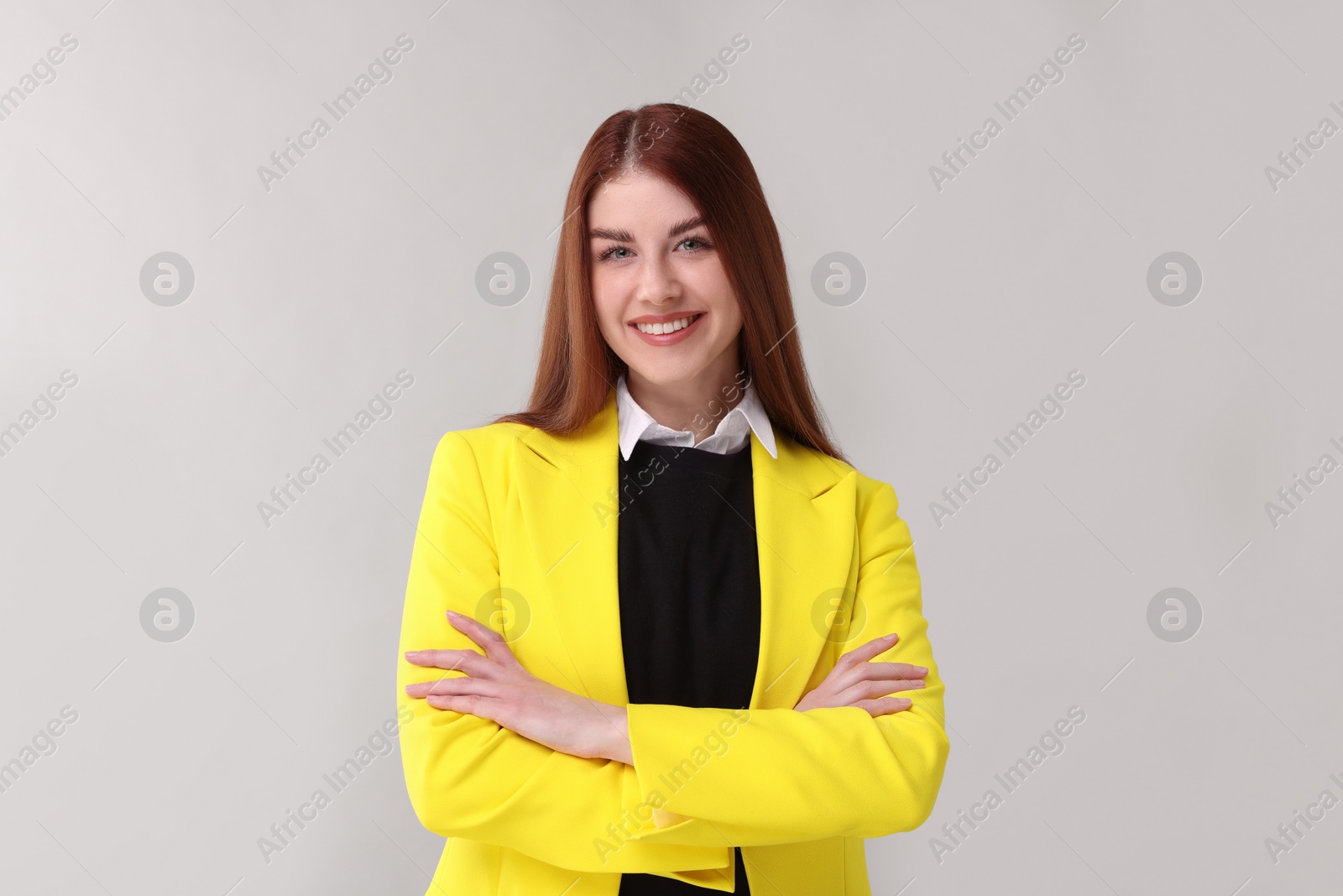 Photo of Portrait of smiling woman with crossed arms on light grey background