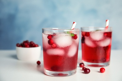 Photo of Tasty refreshing cranberry cocktail with mint on white table